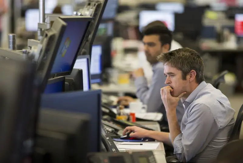 Dealers work on the IG Group trading floor in London, Britain