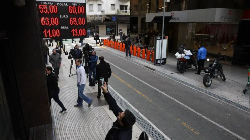 A man takes a photo of the exchange rate displayed on a currency exchange board in Buenos Aires.